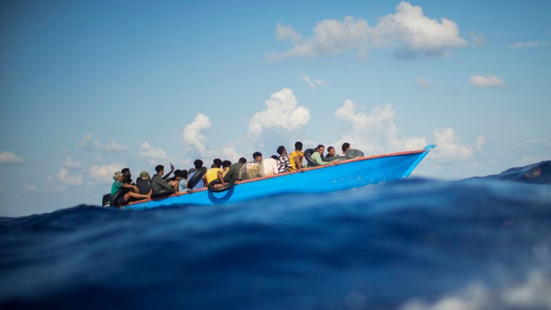 Migranten sitzen in einem Holzboot südlich der italienischen Insel Lampedusa auf dem Mittelmeer.