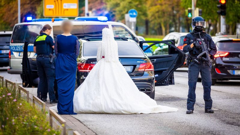 Polizisten kontrollieren Teilnehmer eines Hochzeitskorsos und ihre Fahrzeuge.