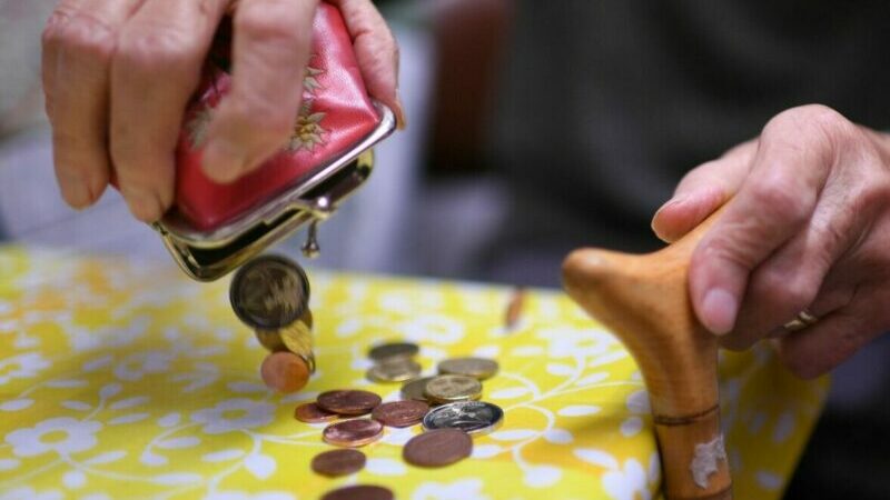 Eine Rentnerin schüttet den Inhalt ihres Geldbeutels auf den Küchentisch.