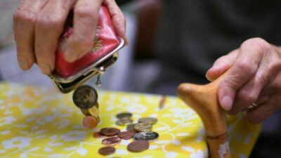 Eine Rentnerin schüttet den Inhalt ihres Geldbeutels auf den Küchentisch.