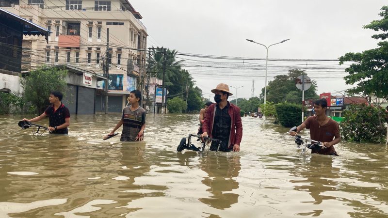 Anwohner schieben ihre Fahrräder durch eine überschwemmte Straße in Bago.