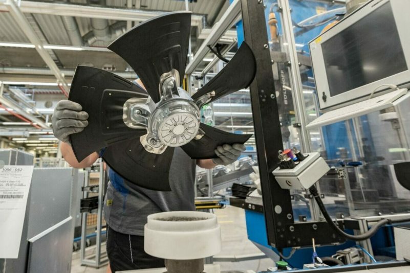 Ein Mitarbeiter eines Herstellers von Ventilatoren und Elektromotoren montiert einen Lüfter.