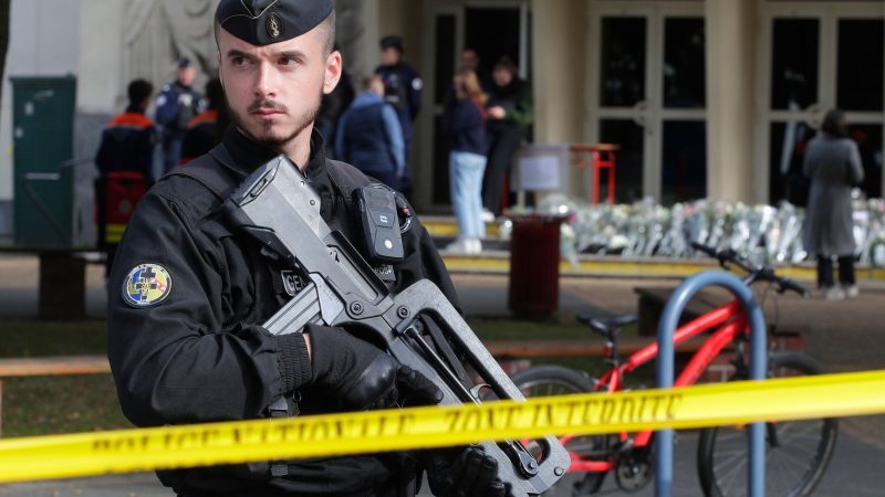 Ein schwer bewaffneter französischer Polizist vor einem Gymnasium (Archivbild). In Frankreich häufen sich seit einigen Tagen Bombendrohungen, insbesondere gegen Schulen - nun auch gegen mehrere Regionalflughäfen.