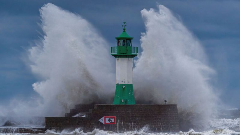 Wellen brechen an einem Leuchtturm in Sassnitz. Ein Sturmtief sorgt an der Ostseeküste für Überschwemmungen und Hochwasser.