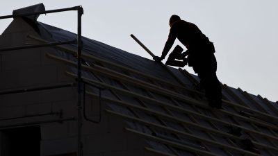 Ein Dachdecker arbeitet auf einem Einfamilienhaus.
