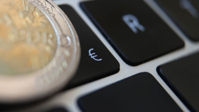 Eine Zwei-Euro-Münze liegt auf der Tastatur eines Laptops neben einem Eurozeichen. Die EBZ hebt die Zinsen vorerst nicht weiter an. (Symbolbild)