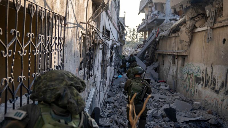 Israelische Soldaten gehen zwischen zerstörten Häusern: Israels Militär hat nach eigenen Angaben die Stadt Gaza umstellt.