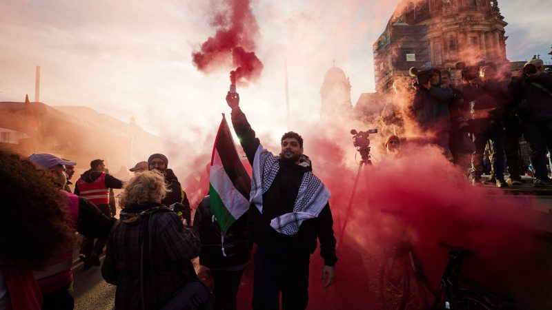 Teilnehmer einer Pro-Palästina-Kundgebung auf der Straße Unter den Linden zünden Pyrotechnik.