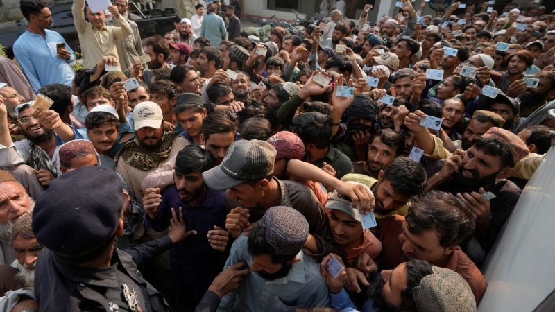 Pakistanische Polizeibeamte versuchen, Einwanderer in Karachi zu kontrollieren. Pakistan hat Tausende afghanische Flüchtlinge abgeschoben.