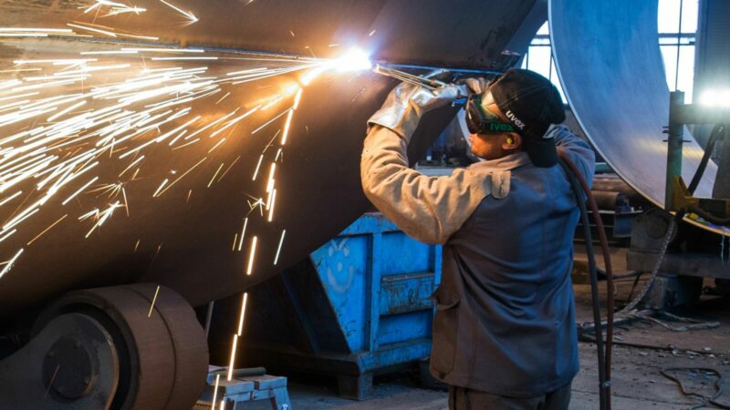 Ein Mann aus Somalia, der zuvor als Schweißer ausgebildet wurde, arbeitet in einer Firma an einem Stahlsegment.