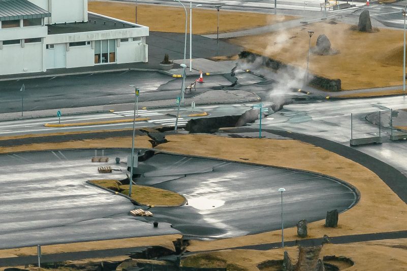 Aus Rissen im Boden in der isländsichen Stadt Grindavik steigt Rauch auf (Luftaufnahme mit Drohne).