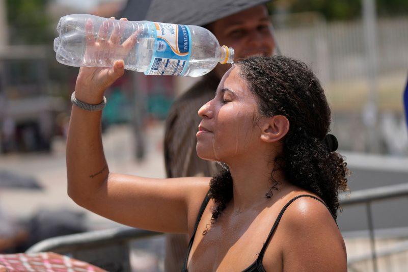 Ein Fan von Taylor Swift kühlt sich vor dem Konzert der "Eras"-Tour vor dem Olympiastadion mit einer Wasserflasche ab.