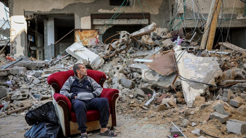Ein palästinensischer Mann sitzt in einem Sessel vor einem zerstörten Gebäude in Gaza-Stadt.