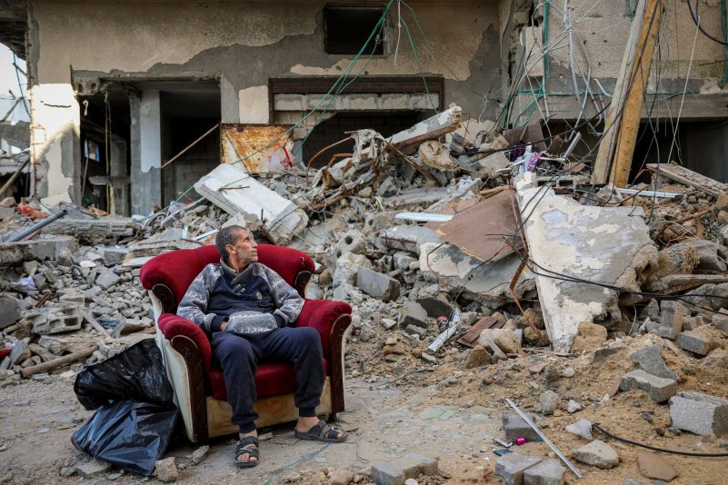 Ein palästinensischer Mann sitzt in einem Sessel vor einem zerstörten Gebäude in Gaza-Stadt.