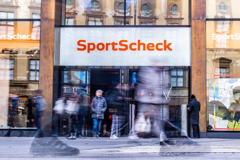 Personen gehen an einer Sportscheck-Filiale in der Münchener Fußgängerzone vorbei.
