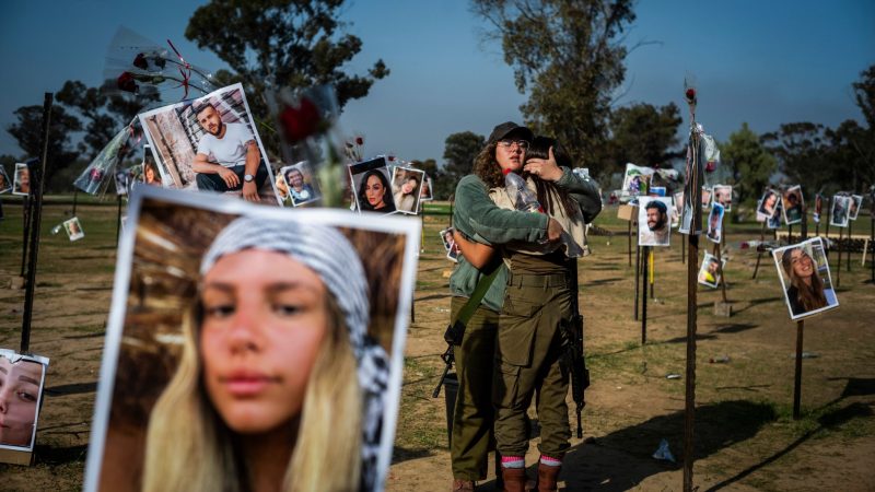 Israelische Soldatinnen stehen zwischen Fotos getöteter Israelis am Ort des Massakers beim Re'im-Musikfestival in der Negev-Wüste.