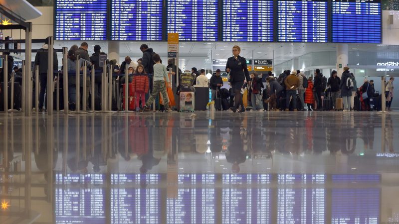 Passagiere stehen am Münchener Flughafen beim Check-in.