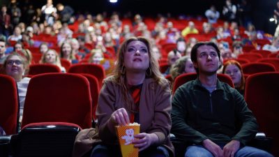Menschen sitzen in Warschau in einem Kino, um sich die Rede von Polens Ministerpräsident Mateusz Morawiecki anzuschauen.