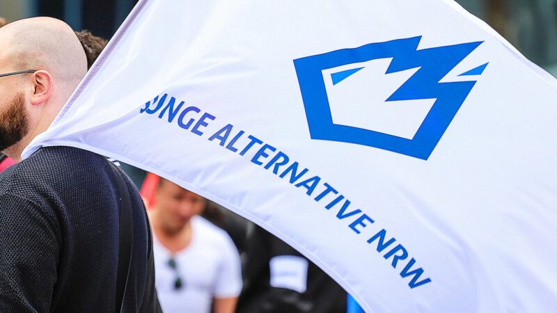 Ein Mitglied der «Jungen Alternative» (JA) trägt auf einer Wahlkampfveranstaltung in Dortmund eine Fahne mit dem Logo der Organisation.