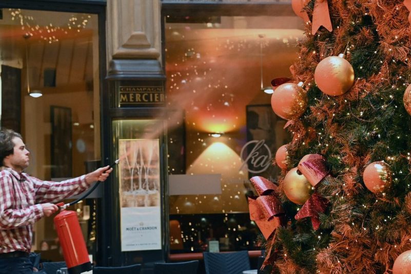 Ein Mitglied der Protestgruppe "Letzte Generation" besprüht einen Weihnachtsbaum in der Leipziger Mädler-Passage.