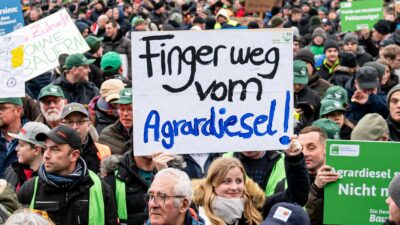 Auf einer Demonstration des Deutschen Bauernverbandes unter dem Motto «Zu viel ist zu viel! Jetzt ist Schluss!» hält jemand ein Schild mit der Aufschrift „Finger weg vom Agrardiesel“ hoch.