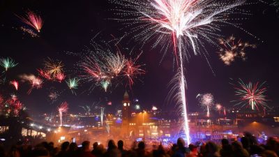 Zahlreiche Menschen feiern den Jahreswechsel auf Sankt Pauli über den Landungsbrücken am Hamburger Hafen.
