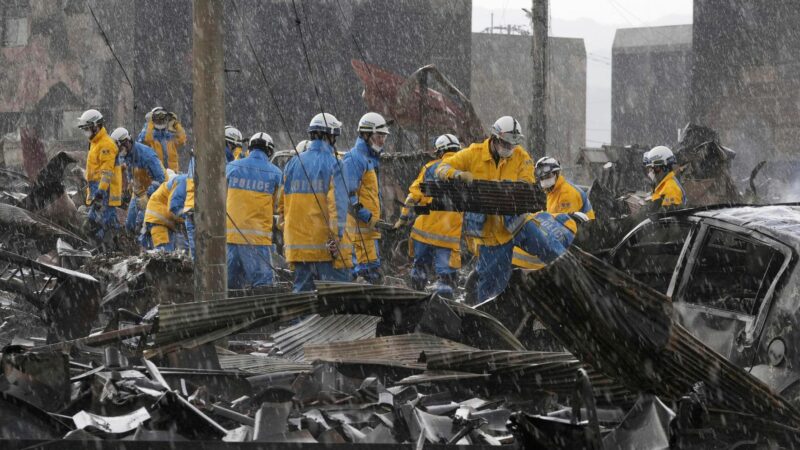 Polizeibeamte bin den Trümmern auf einem Markt in der Präfektur Ishikawa.