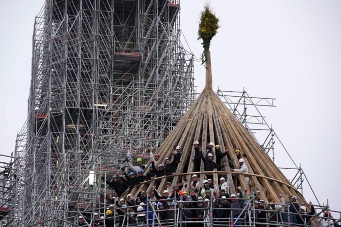 Mit einem Blumengesteck feiern die Arbeiter den Abschluss des Wiederaufbaus des Dachstuhls. Die Kathedrale Notre Dame in Paris war 2019 durch einen Brand schwer beschädigt worden.