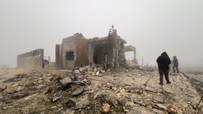 Syrer blicken auf eine verlassene medizinische Einrichtung, die nach Angaben der freiwilligen Rettungsorganisation White Helmets am späten Montagabend von iranischen Raketen getroffen wurde.