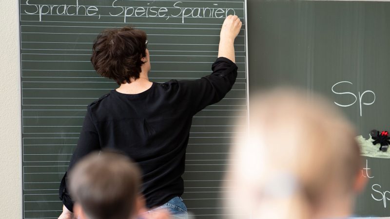Eine Lehrerin schreibt an die Tafel: An Grundschulen könnte es bald genug Lehrkräfte geben.