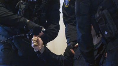 Justitzbeamte nehmen dem Angeklagten im Gerichtssaal vom Landgericht Magdeburg die Handschellen ab.