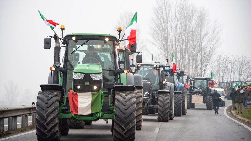 Landwirte fahren mit ihren Traktoren eine Straße an der Mautstelle von Melegnano in der Nähe von Mailand entlang.