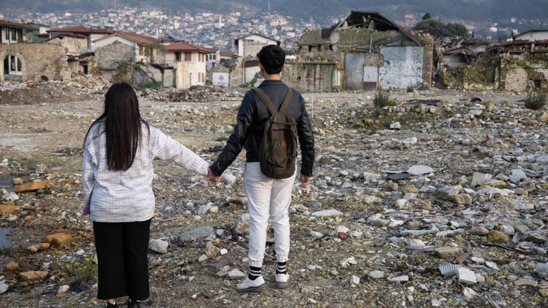 Die Geschwister Arzu (l) und Mehmet stehen in den Trümmern der Altstadt von Antakya. Beide waren bei dem Beben vor einem Jahr verschüttet worden.
