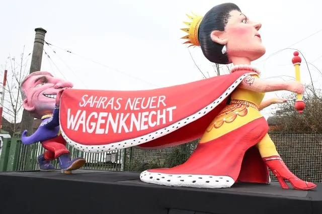 «Sahras neuer Wagenknecht» steht auf dem Umhang einer Figur auf einem Mottowagen, der zum Rosenmontagszug in Düsseldorf gefahren wird.
