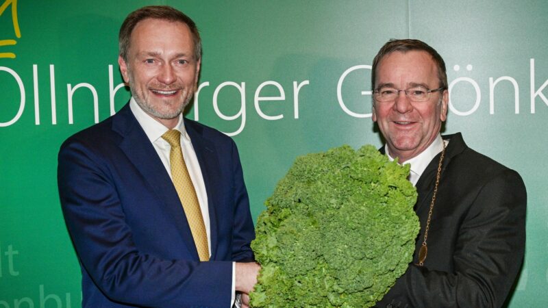 Christian Lindner (l) übergibt dem neuen Oldenburger Grünkohlkönig Boris Pistorius mit einer Grünkohlpflanze sein Ehrenamt.