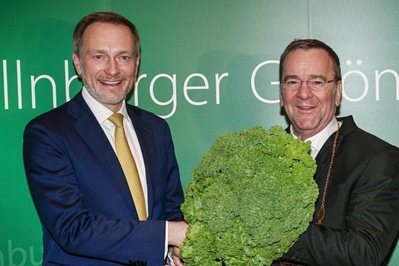 Christian Lindner (l) übergibt dem neuen Oldenburger Grünkohlkönig Boris Pistorius mit einer Grünkohlpflanze sein Ehrenamt.