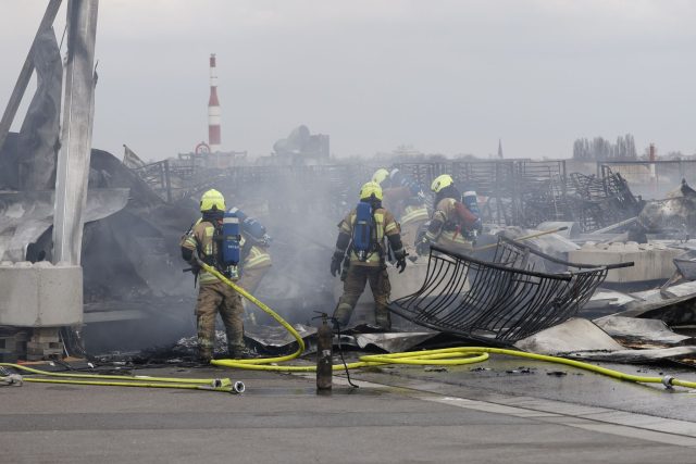 Die Feuerwehr löscht die Brandstelle bei der Flüchtlingsunterkunft am ehemaligen Flughafen Tegel. Die Nachlöscharbeiten sind inzwischen abgeschlossen.
