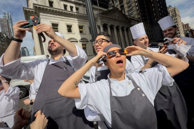Angestellte eines Restaurants im Flatiron District von Manhattan machen eine Pause, um die Sonnenfinsternis zu betrachten.