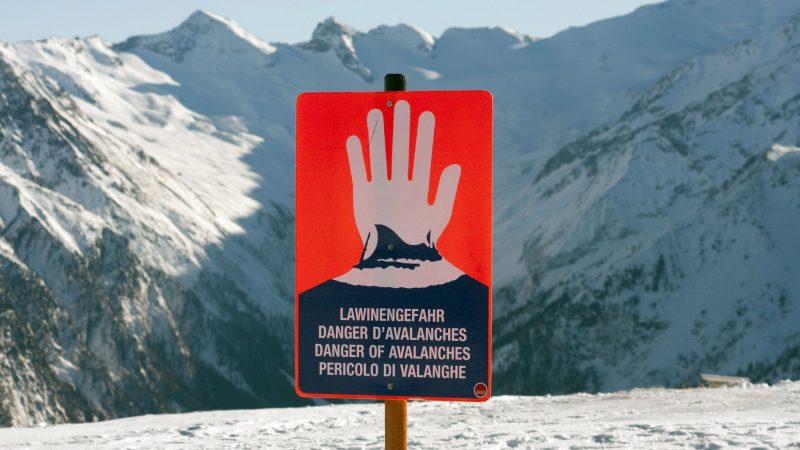 Ein Schild warnt in einem Skigebiet in den Alpen vor Lawinengefahr.