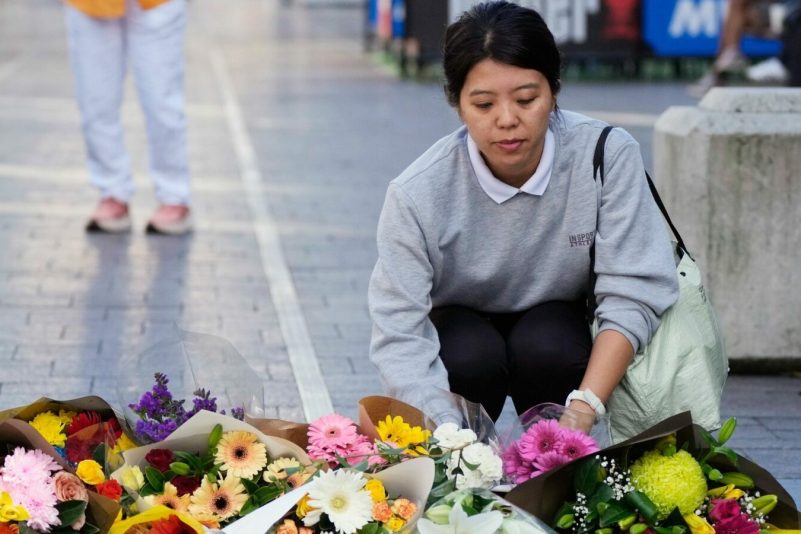 Eine Frau bringt Blumen zu einer improvisierten Gedenkstätte an der Bondi Junction.