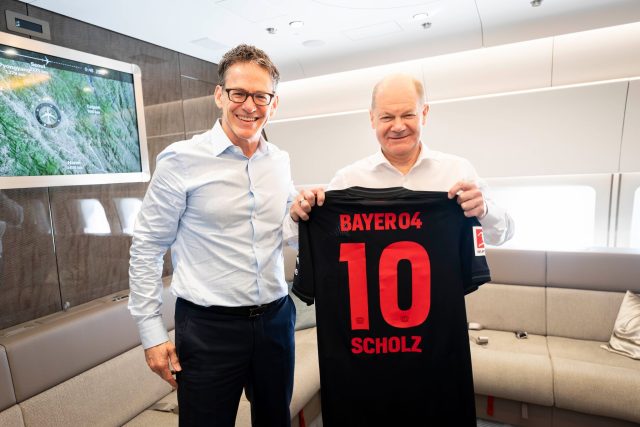 Bayer-CEO Bill Anderson (l.) überreicht Bundeskanzler Olaf Scholz (SPD) ein signiertes Trikot des neuen Bundesliga-Meisters Bayer Leverkusen.