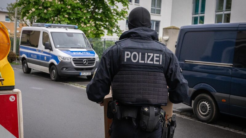 Ein Polizist trägt bei einem Einsatz in Bonn einen Karton mit beschlagnahmtem Material aus einem Gebäude.