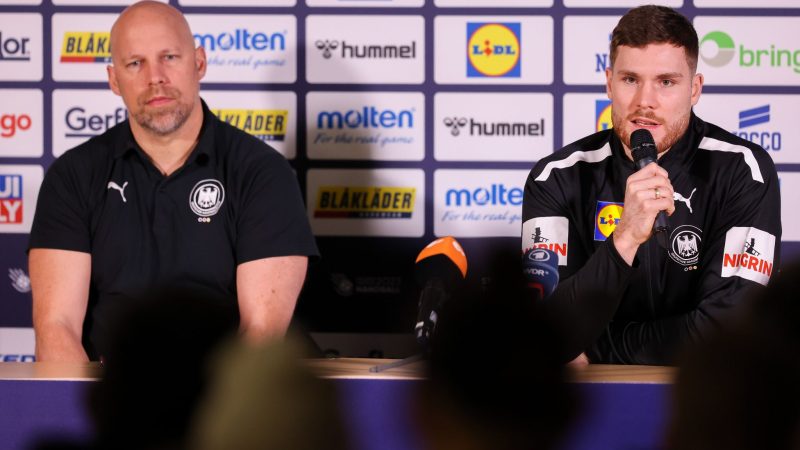 Axel Kromer (l) und Kapitän Johannes Golla sitzen während einer Pressekonferenz auf dem Podium.