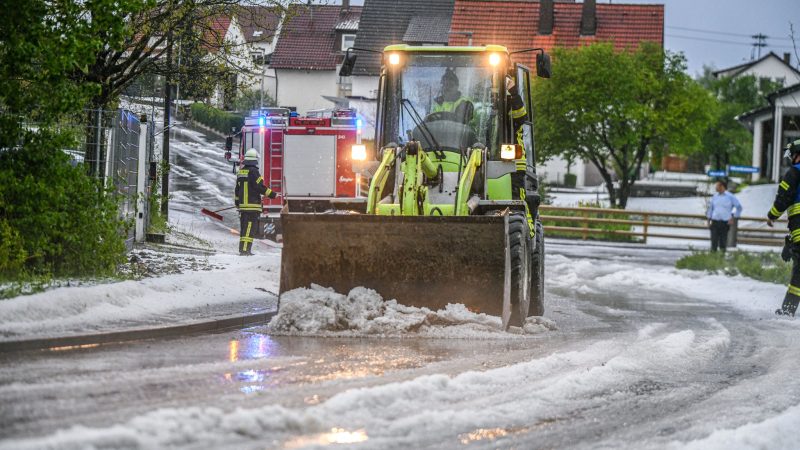 Einsatzkräfte der Feuerwehr räumen nach einem Hagelscheuer eine Straße in Söhnstetten im Landkreis Heidenheim (Baden-Württemberg).