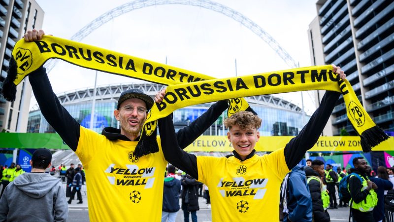 Zwei Fans von Borussia Dortmund stehen mit einem BVB-Fan-Schal vor dem Wembley-Stadion.