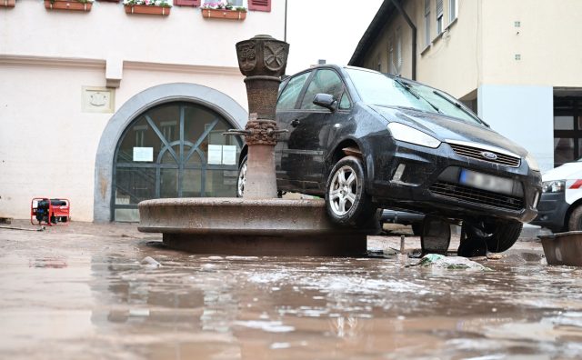 Auf einem Brunnen in Rudersberg hängt ein durch das Hochwasser weggespültes Auto.