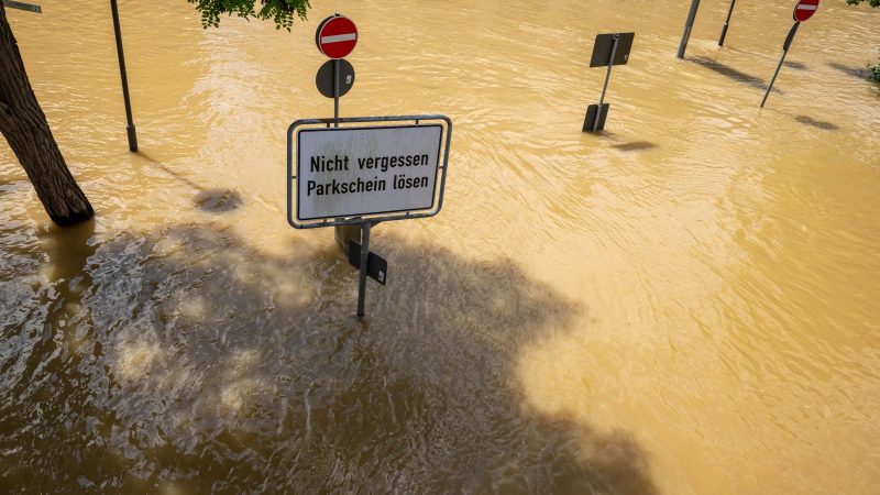 In Bayern herrscht nach heftigen Regenfällen vielerorts weiter Hochwasser. Ein Schild mit der Aufschrift „Nicht vergessen, Parkschein lösen“ in Passau deutet auf einer überfluteten Parkplatz hin.