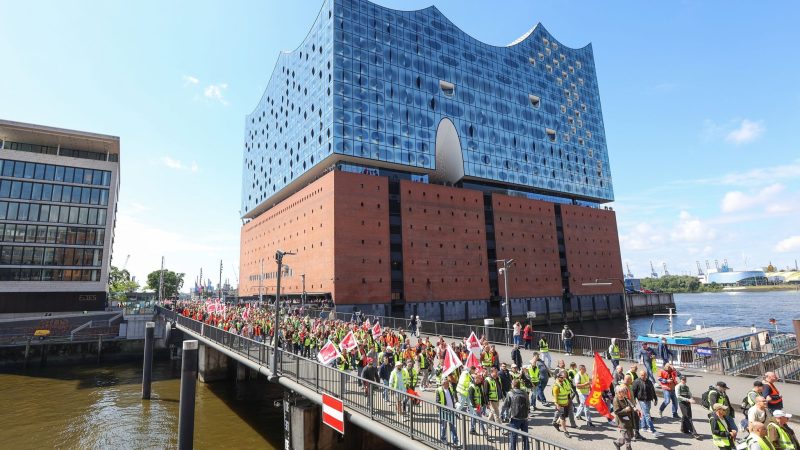 Streikende Hafenarbeiter ziehen bei einer Demonstration an der Hamburger Elbphilharmonie entlang.