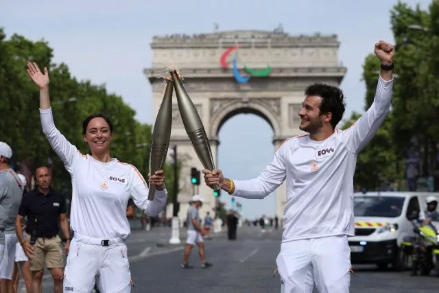 Olympia-Countdown: Fackelträger Nina Metayer, eine französische Konditorin, und Amir, ein französisch-israelischer Sänger, halten die olympische Fackel auf der Avenue des Champs-Elysees.