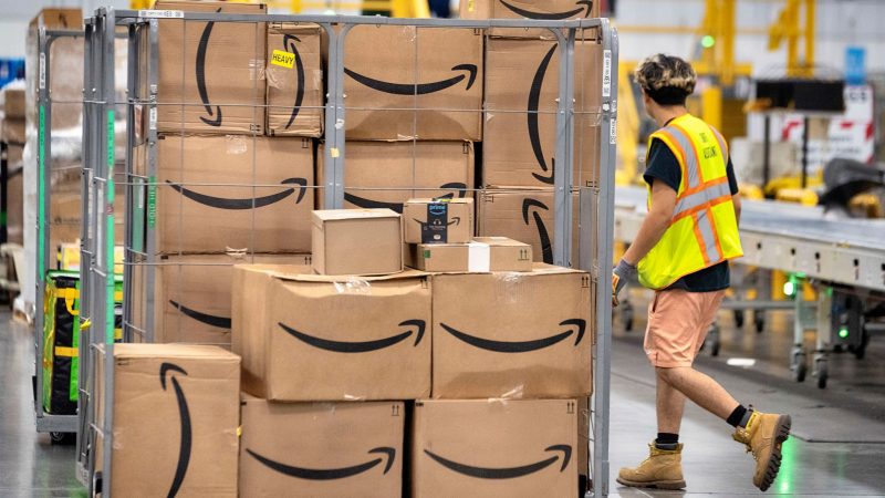 Ein Amazon-Mitarbeiter geht an Paketen vorbei, die auf einem Wagen auf dem Boden der DAX7-Lieferstation während des jährlichen Prime Day-Events von Amazon liegen.
